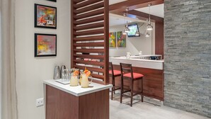 A modern kitchen with a wooden island, bar stools, and a stone accent wall.