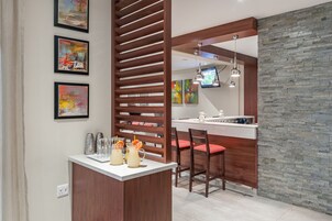 Cozinha moderna com ilha de madeira, banquetas de bar e parede decorativa em pedra.
