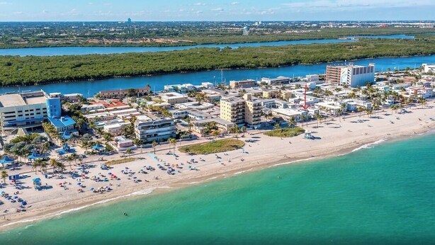 Une vue aérienne d’une ville côtière avec une plage, des bâtiments et une rivière.
