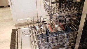 Une cuisine équipée d’un lave-vaisselle, de meubles blancs et d’un évier en acier inoxydable.
