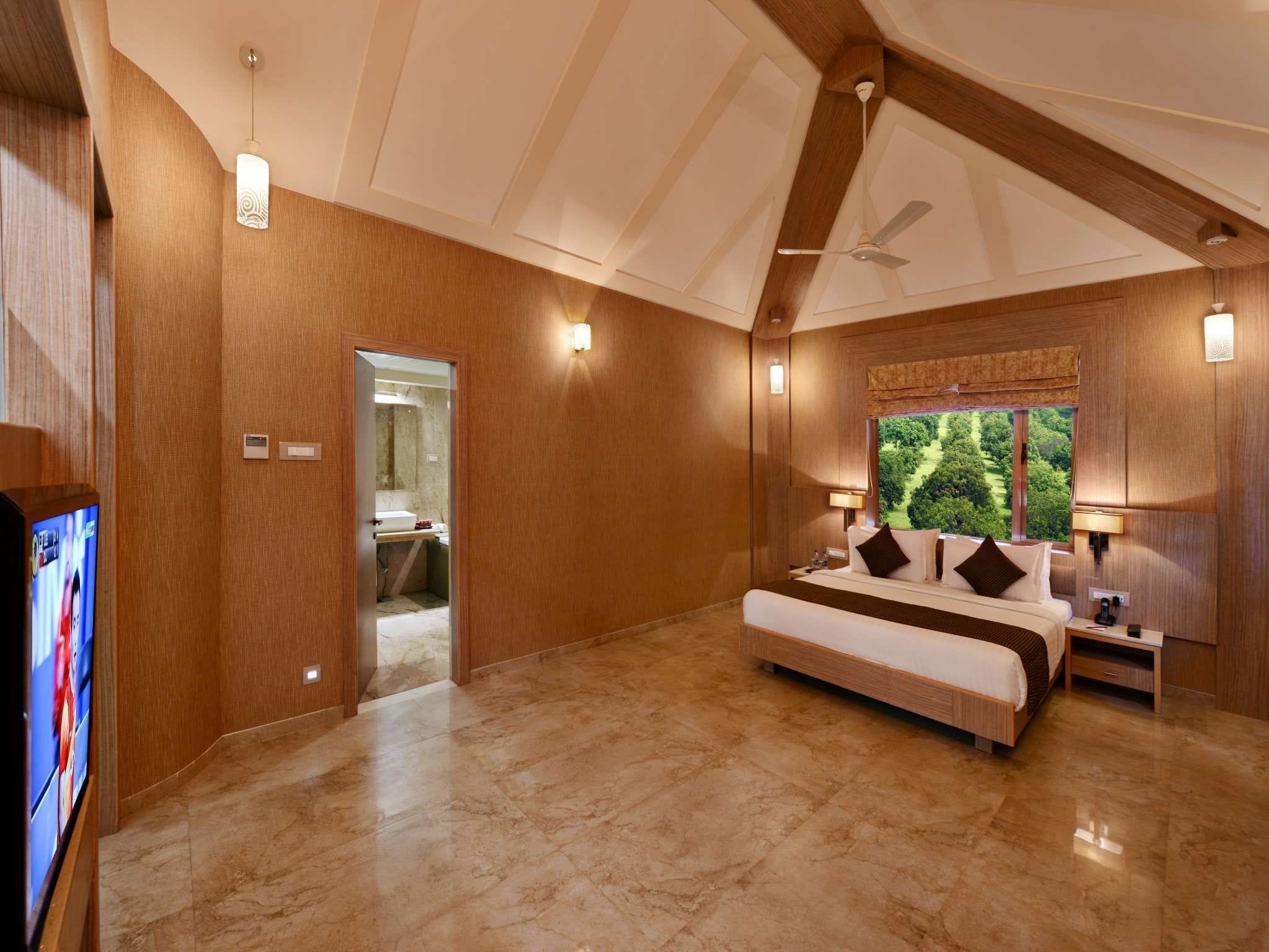 A spacious bedroom with a large bed, a ceiling fan, and a view of the outdoors.