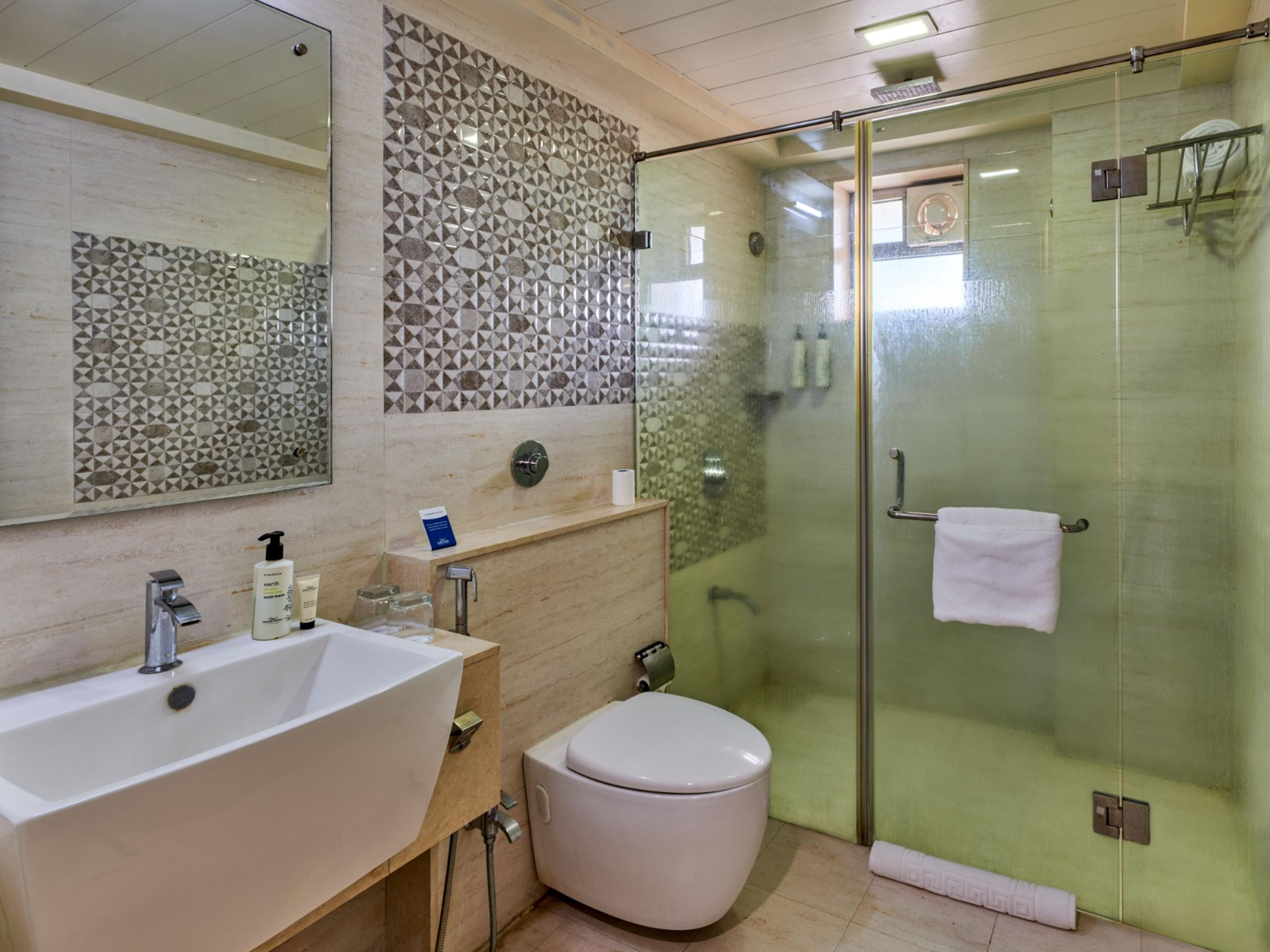 A bathroom with a glass-enclosed shower, a white sink, and a toilet.