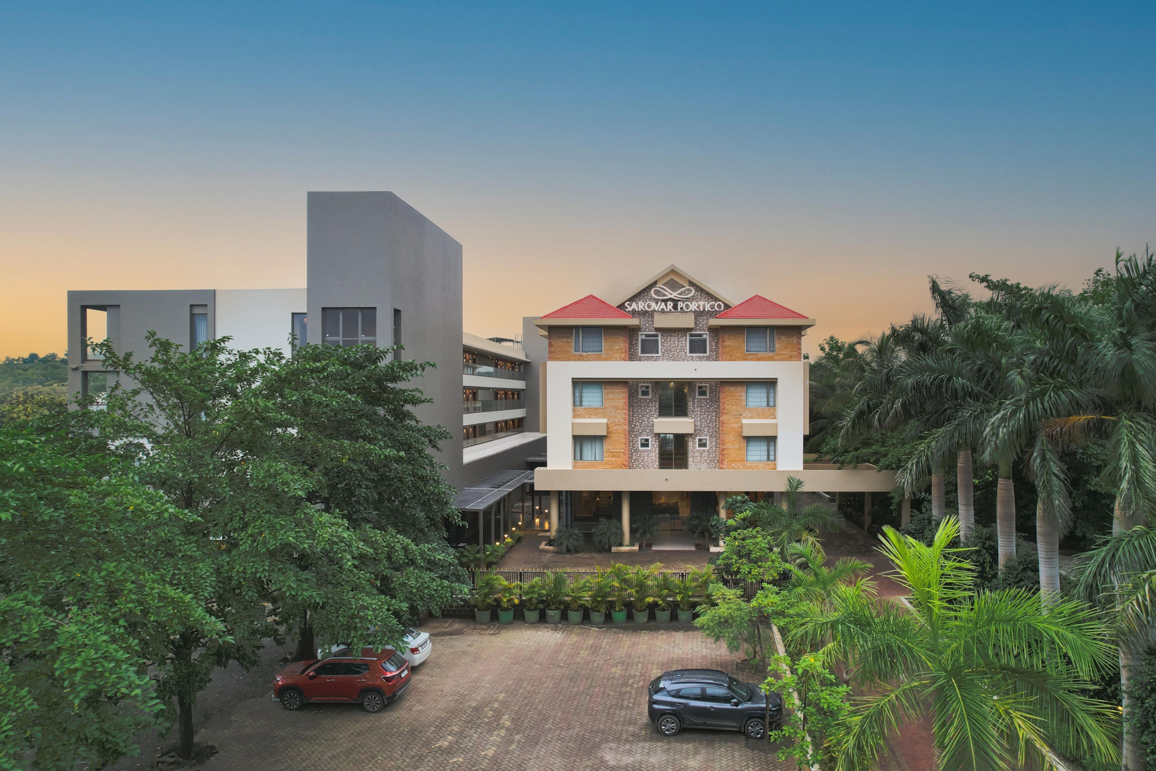 A multi-story hotel with a modern architectural design, featuring a prominent entrance and a parking area.