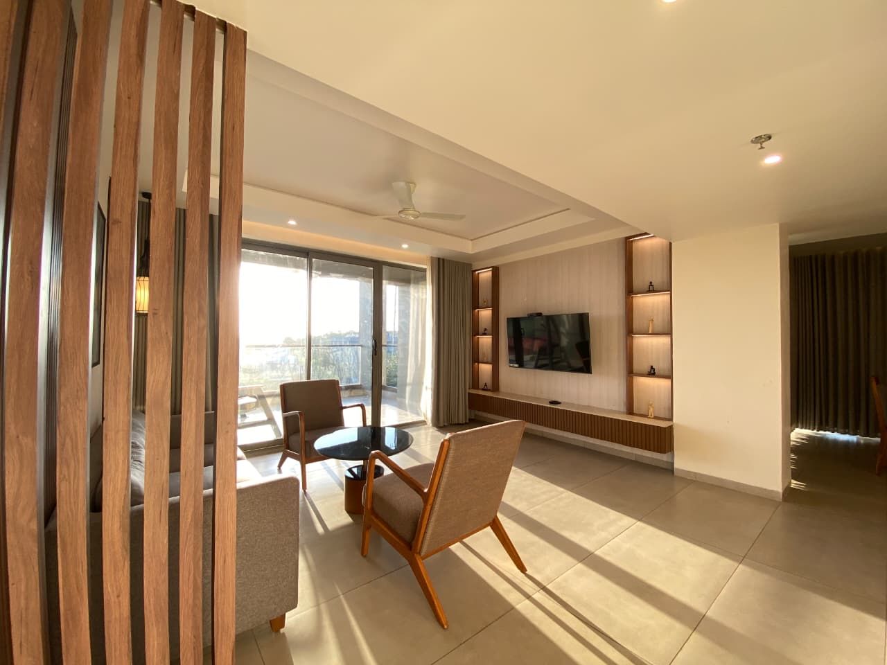 Una sala de estar moderna con un televisor de pantalla plana, una zona de comedor con mesa y sillas, y un gran ventanal con vistas.