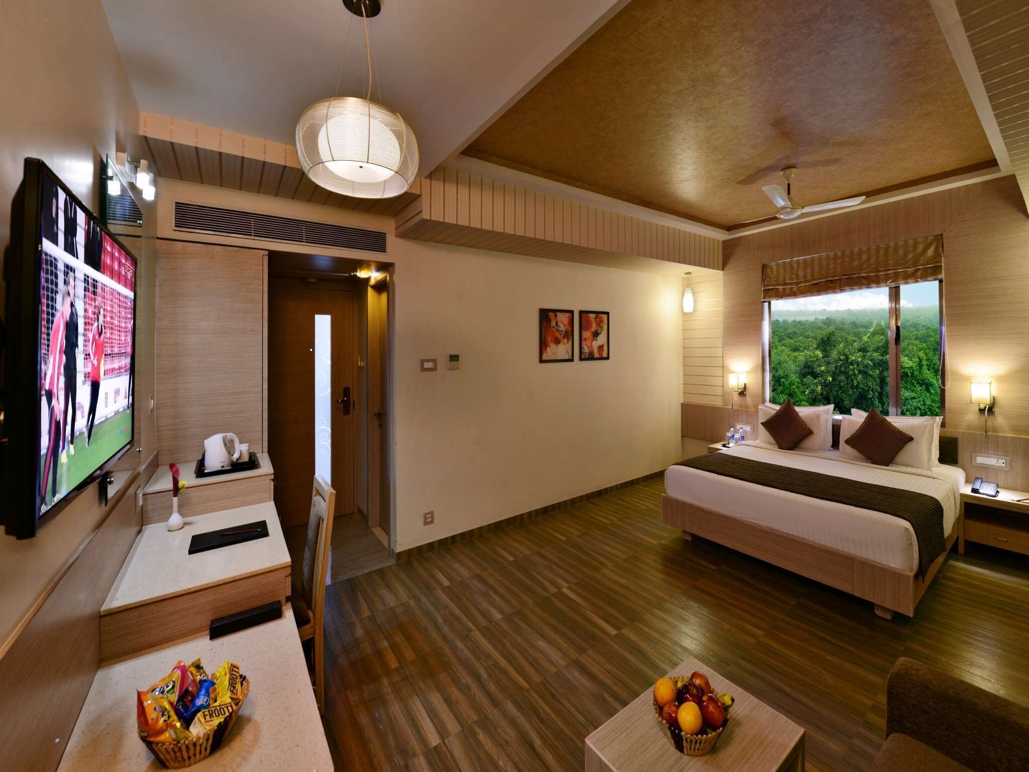 A hotel room with a bed, a TV, a desk, and a fruit basket.