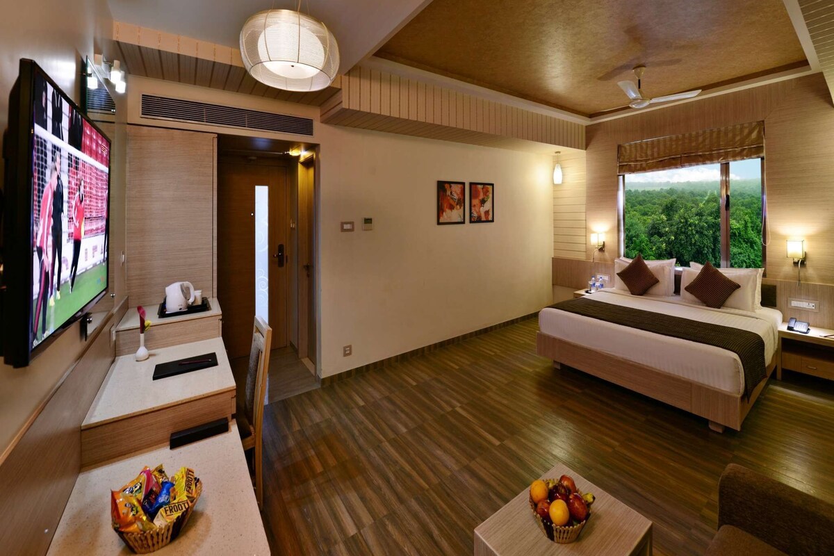 A hotel room with a bed, a TV, a desk, and a fruit basket.