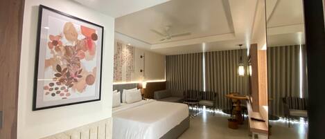 Quarto de hotel moderno com uma cama grande, uma escrivaninha, uma cadeira, um espelho e um ventilador de teto.
