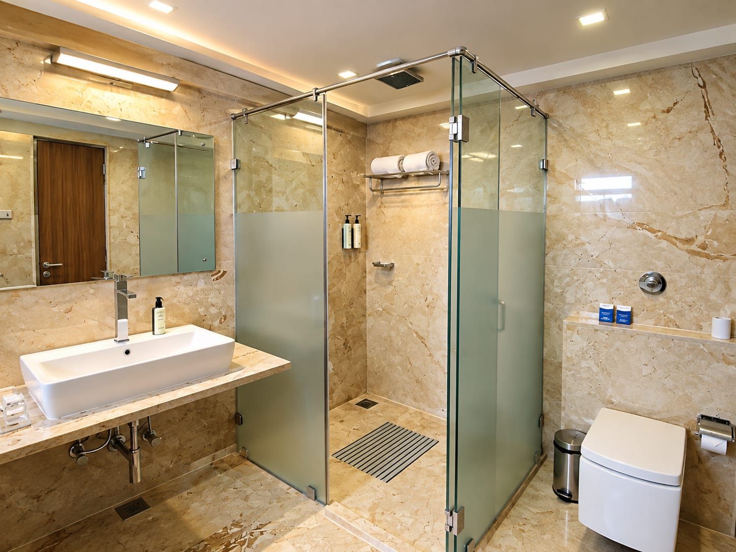 A modern bathroom with a glass-enclosed shower, a sink with a mirror, and a toilet.