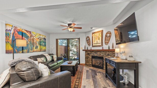 A living room with a fireplace, a sofa, a coffee table, and a television mounted on the wall. - Private Shuttle in Winter, Free Bus Route, Convenient Location + Hot Tub & Pool (Steamboat Springs)