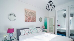 A bedroom with a large bed, two bedside tables with lamps, a mirror, and a colorful artwork on the wall. - Bryn-y-Mor Cottage/ Romantic / Fireplace/Couples (Leura)