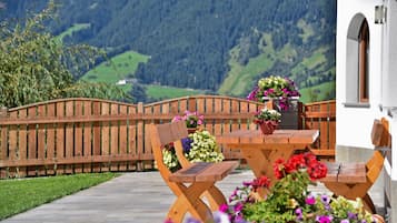 A wooden table and chairs set outdoors with a mountain backdrop.