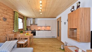 Tunnelmallinen, mökin tyylinen huone, jossa on puuseinät, ruokailutila ja keittiö.