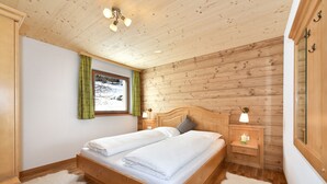 Une chambre à coucher aux murs lambrissés, avec un lit, deux tables de chevet et une fenêtre avec des rideaux.