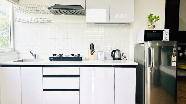 A modern kitchen with white cabinets, a stainless steel refrigerator, a microwave, and a gas stove.