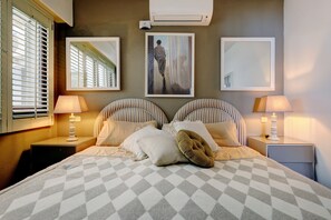 A hotel room with a large bed, two bedside tables, a mirror, and a painting on the wall.