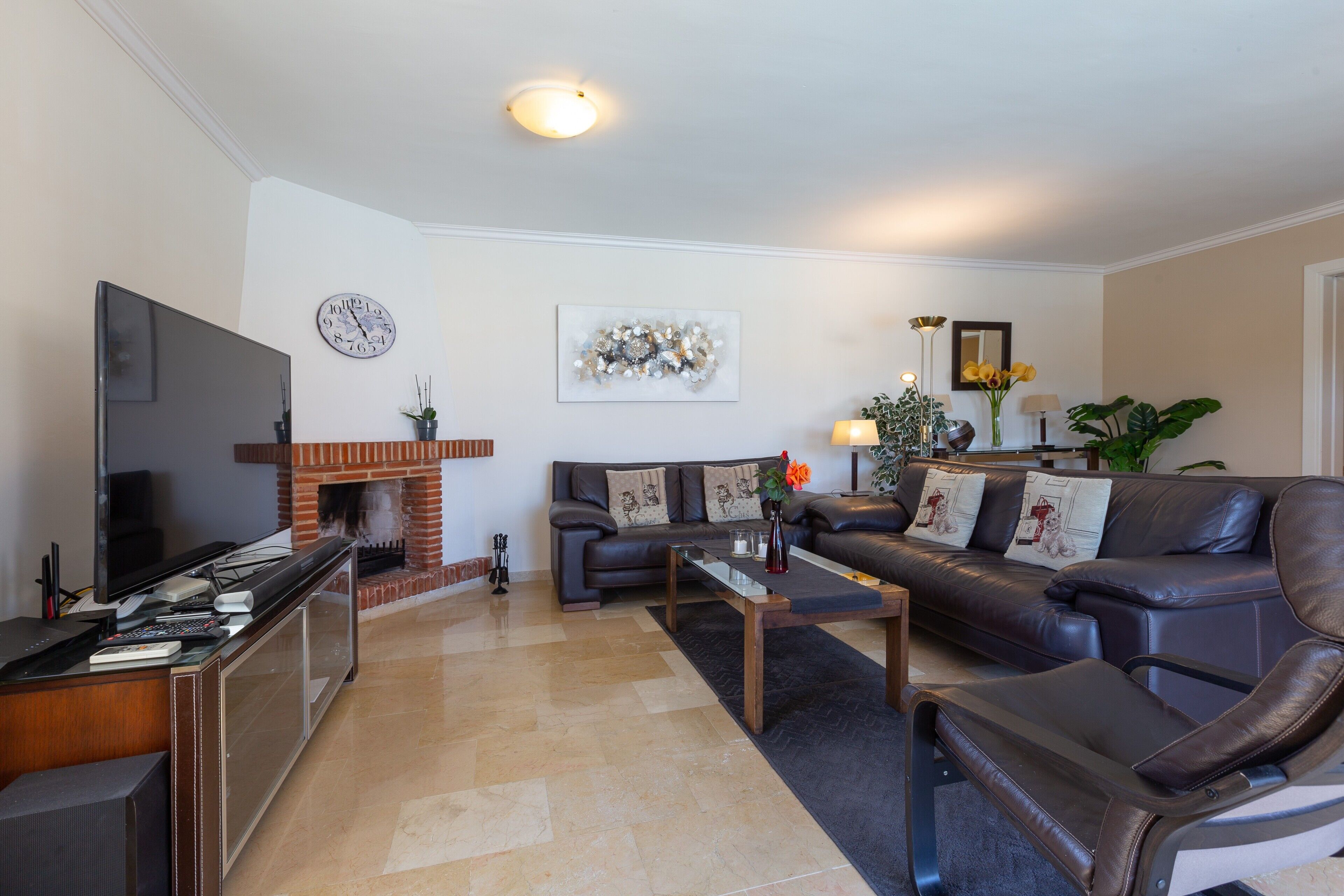 A living room with a flat-screen TV, leather sofa, coffee table, and a fireplace.