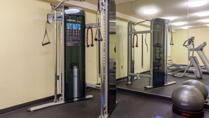 A gym with a squat rack, a bench press, and a mirror. - Travelodge By Wyndham Charles Town/Harpers Ferry (Charles Town)
