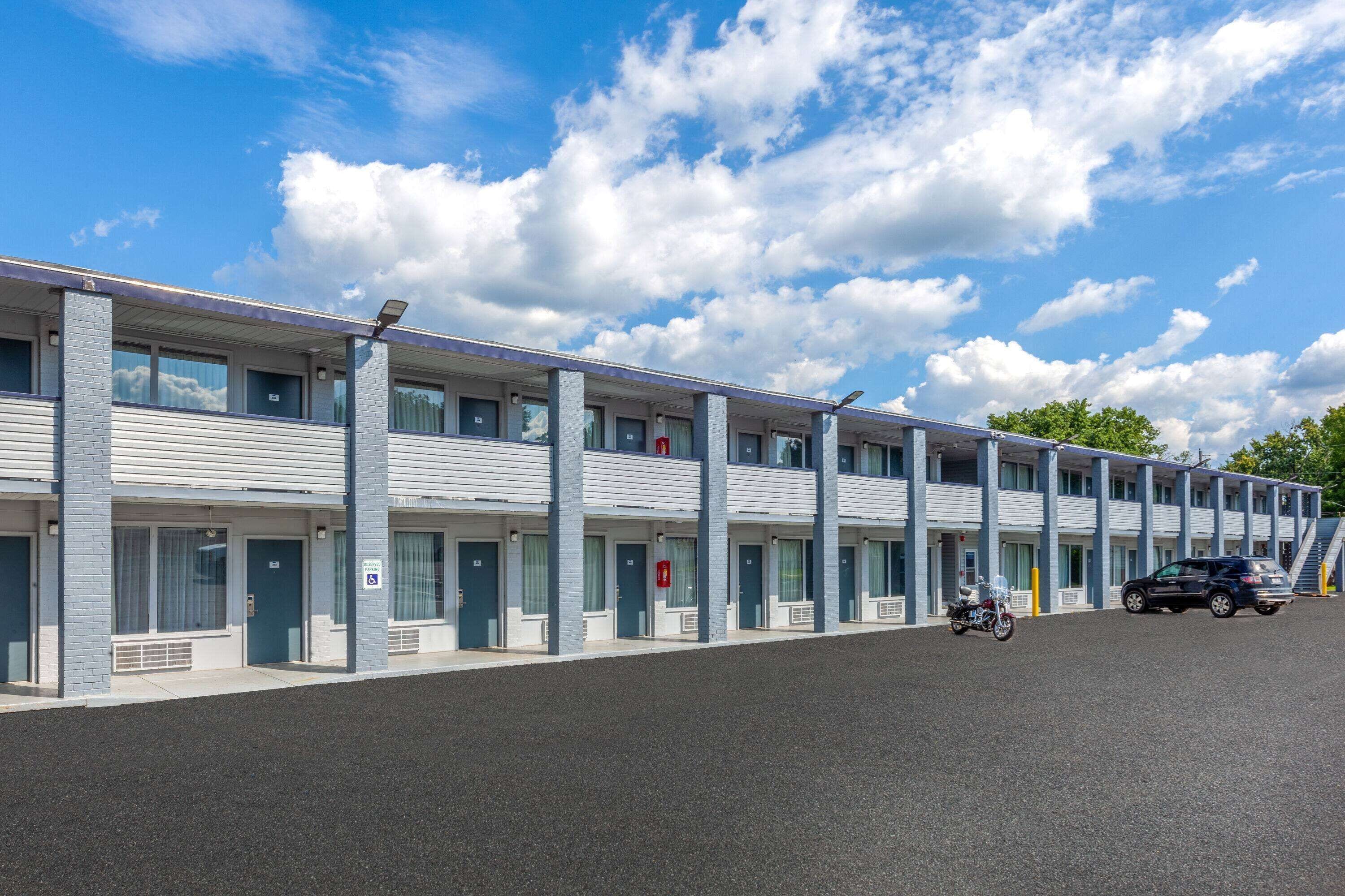 Um motel com uma fileira de quartos, cada um com porta e janelas.