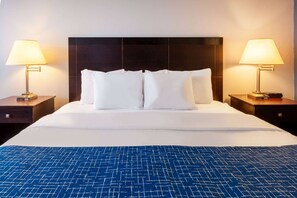 Ein Hotelzimmer mit einem großen Bett, zwei Nachttischen und zwei Lampen.