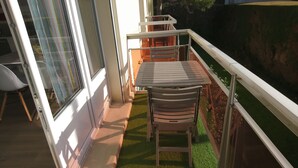 Un balcon avec une table et des chaises, un petit jardin et une vue sur le paysage environnant.