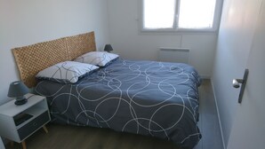 Une chambre à coucher avec un lit, une table de chevet, une lampe, une fenêtre et une porte.