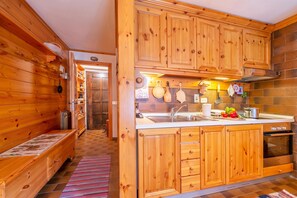 A wooden interior with a kitchen area featuring cabinets, a sink, and a stove. - Casa Cisi ski in-Ski out 20m (Livigno)