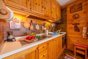A kitchen with wooden cabinets, a sink, and various kitchen utensils. - Casa Cisi ski in-Ski out 20m (Livigno)