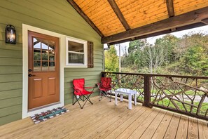 Eine Holzterrasse mit Geländer, einer Tür und zwei roten Stühlen.