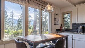 A kitchen with a large window, a table, and chairs.