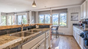 A kitchen with granite countertops, stainless steel sinks, and wooden flooring.