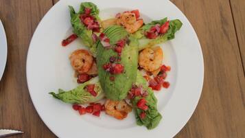 A plate of shrimp and avocado salad on a wooden table.