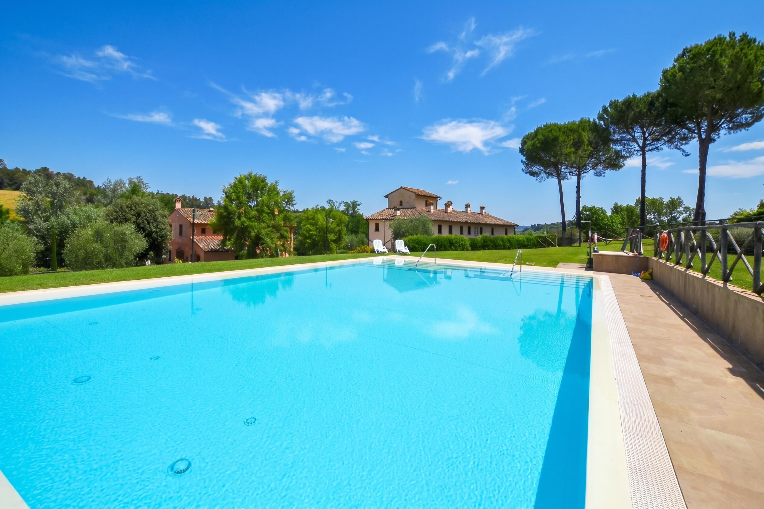 A swimming pool with a clear blue water surface, surrounded by a tiled deck.