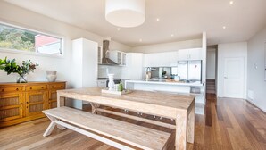 A modern kitchen with white cabinetry, a wooden dining table, and a bench. - Pet Friendly - Cook's Lookout McCrae (McCrae)