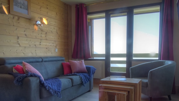 Una habitación acogedora con un sofá gris, una manta azul y una mesa de centro de madera.