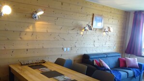 Una habitación con paneles de madera, una mesa larga, dos sofás e iluminación en la pared.