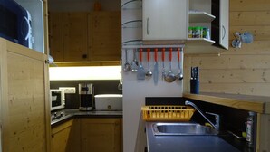 Una cocina con armarios de madera, microondas, cafetera y tostadora.