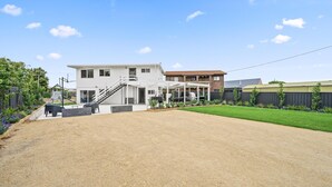Uma casa moderna de dois andares com varanda coberta, entrada de cascalho e gramado bem cuidado.