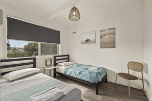 A bedroom with two beds, a window, a chair, and artwork on the wall. - The HardyOne - Aldinga Beach - C21 SouthCoast Holidays (Aldinga Beach)