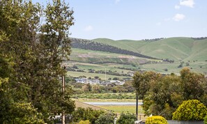 A rural landscape with rolling hills, a small cluster of buildings, and dense greenery. - The HardyOne ~ Aldinga Beach - Stunning Abode in Serene Silver Sands (Aldinga Beach)