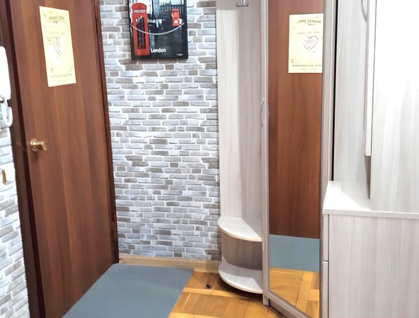 A bathroom with a brick wall, a wooden door, a white sink, and a shower enclosure. - PaulMarie Apartments on Prs.Moskovskiy (Vitebsk)