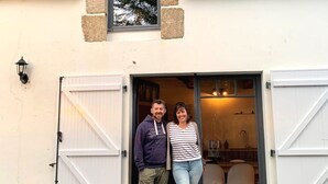A couple standing at the entrance of a building with white wooden doors and a small window above. - Charming Renovated House with Garden in the Heart of Salt Marshes, Close to Guérande and La Baule (Guérande)