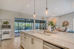 A modern kitchen with a large island, stainless steel appliances, and a view of the outdoors.