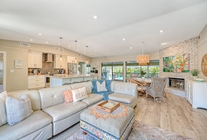 Open plan living area with sofa, coastal decor, and view to kitchen island and large sliding glass doors