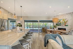 A modern kitchen with a marble countertop, stainless steel appliances, and pendant lighting.