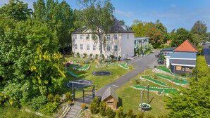Ein großes Gebäude mit Innenhof, umgeben von Bäumen und einem Golfplatz.