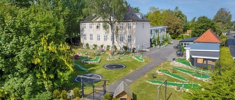 Un edificio grande con un patio interior, rodeado de árboles y un campo de golf.