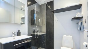 Ein modernes Badezimmer mit einer gläsernen Duschkabine, einem weißen Waschbecken und einer schwarzen Waschtischkommode.