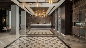 A modern lobby with a reception desk, patterned floor, and contemporary lighting fixtures. - Hotel Santika Premiere Padang (Padang)