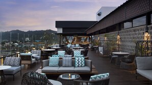 A rooftop bar with outdoor seating, including sofas and chairs, and a view of the cityscape. - Hotel Santika Premiere Padang (Padang)