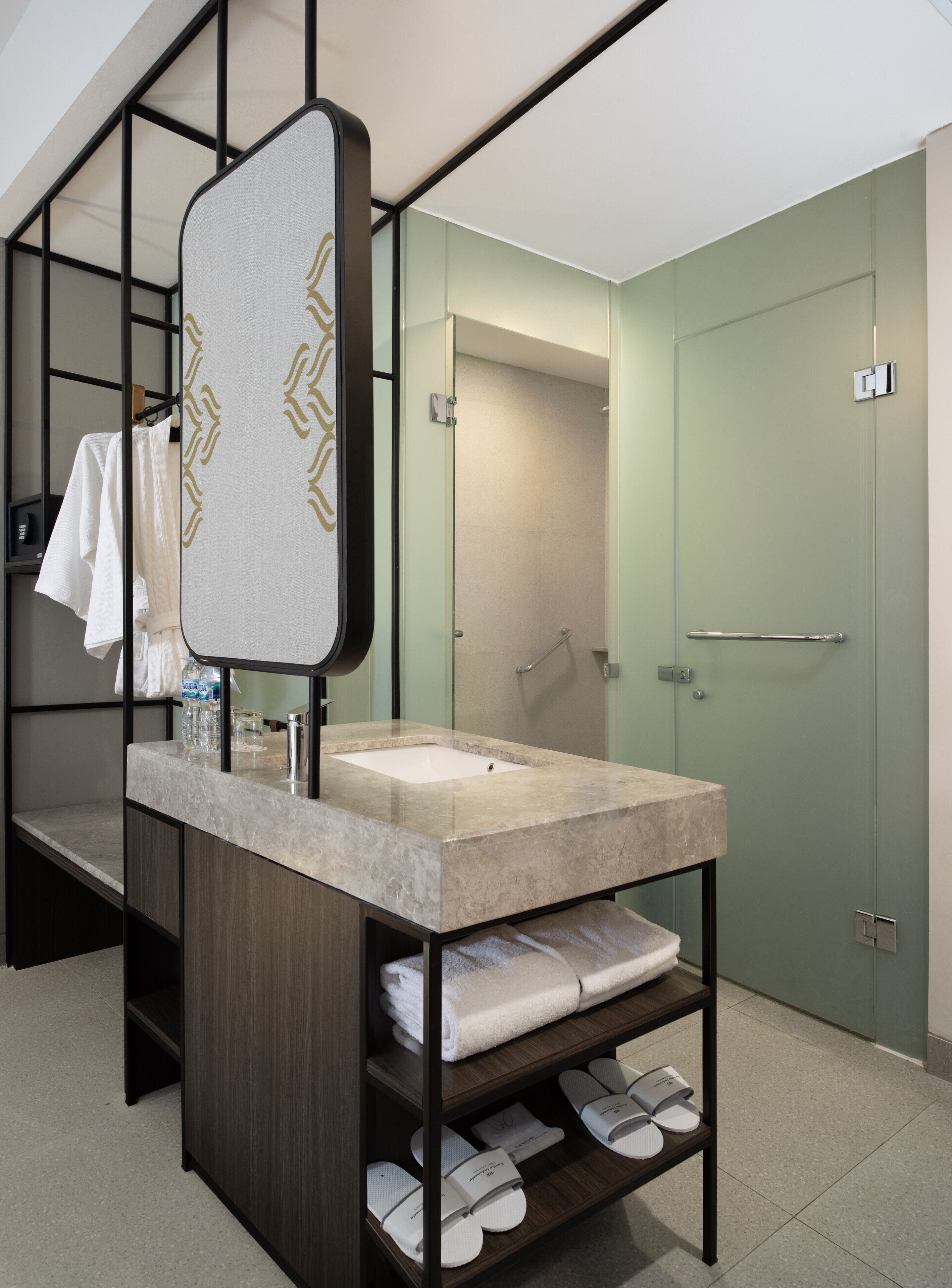 A modern bathroom with a large mirror, a sink, and a shower. There are shelves with towels and toiletries.